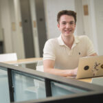student poses for photo with laptop