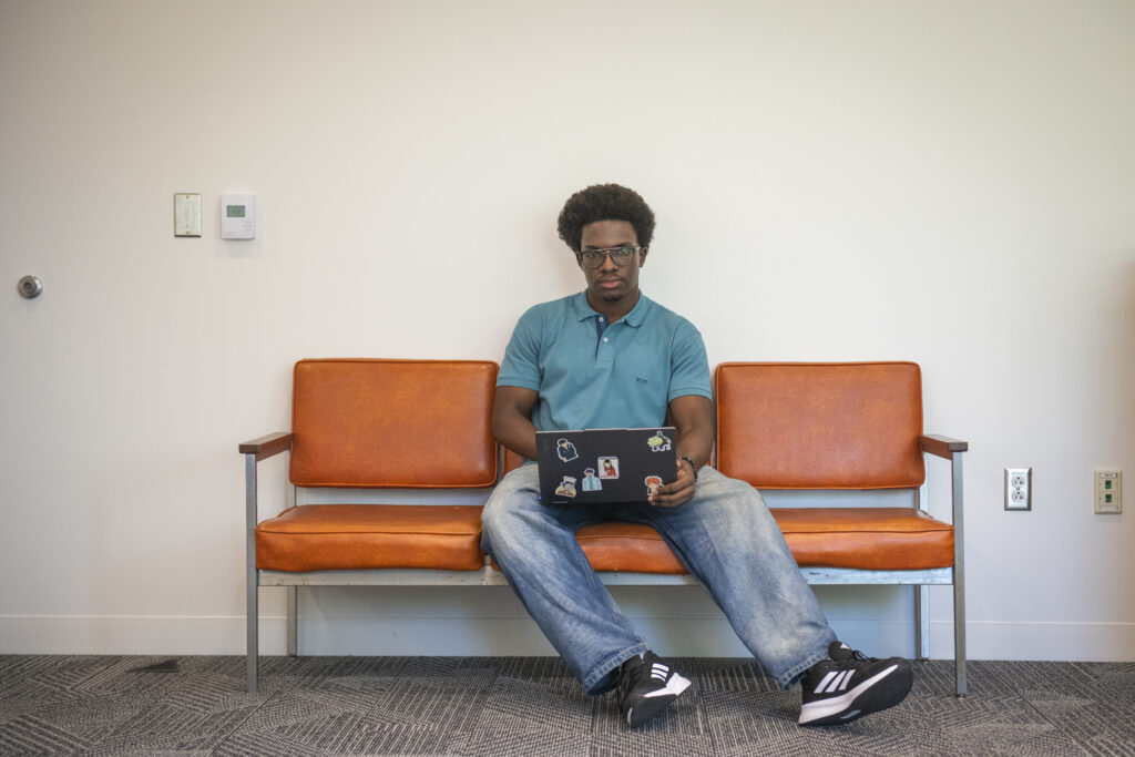 student in blue shirt sits on orange bench