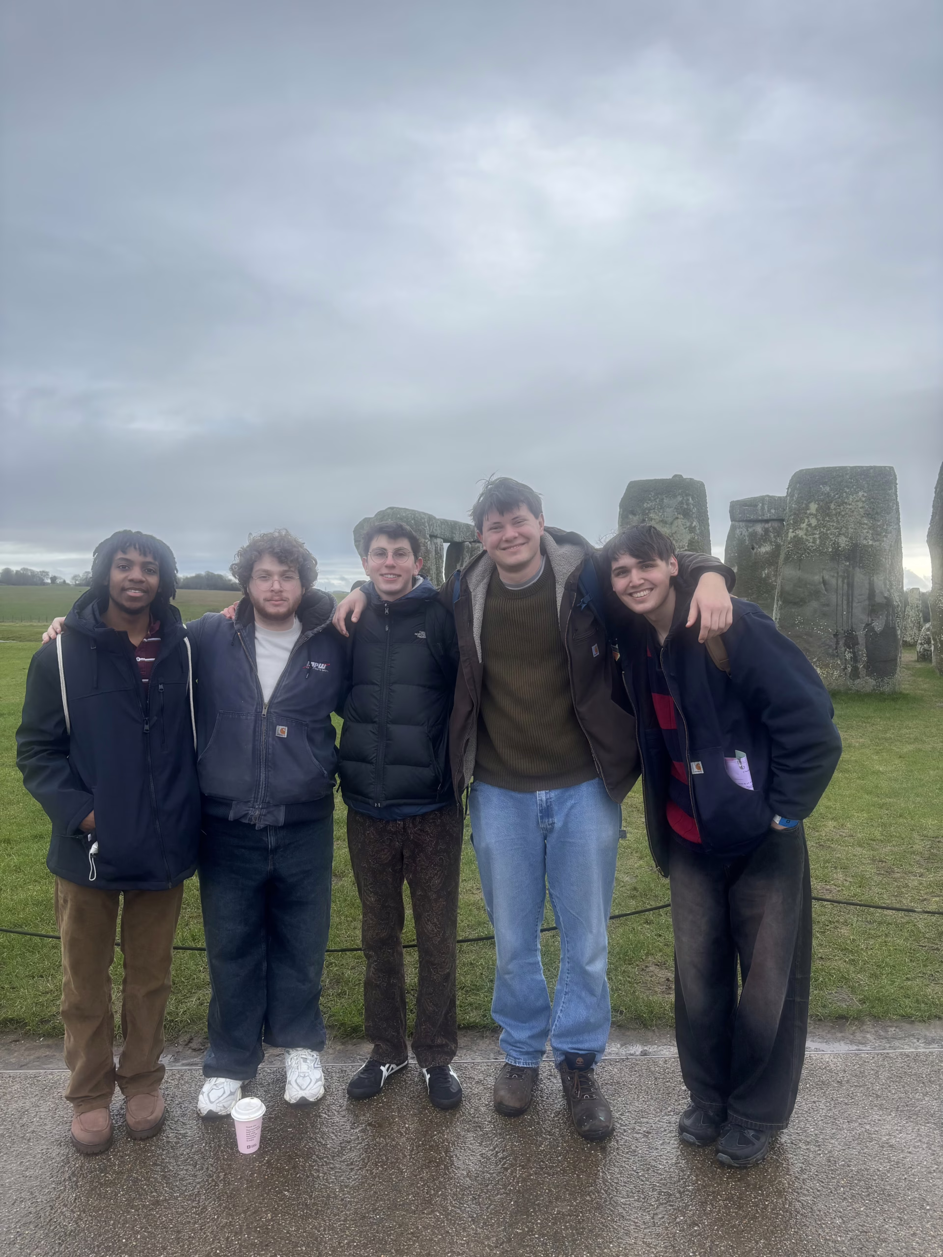 five people pose for photo in front of Stonehenge