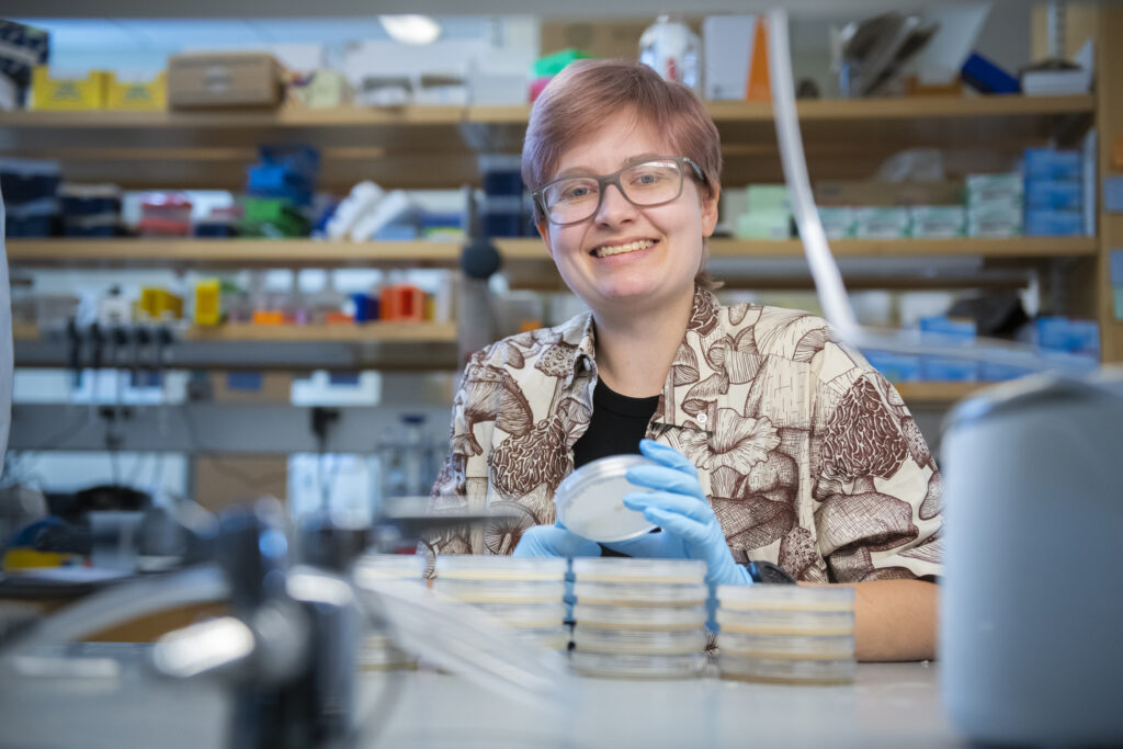 doctoral student smiles at camera in lab