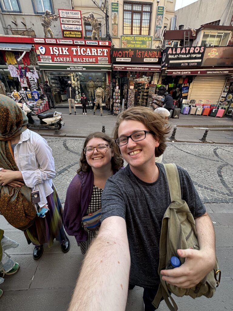 selfie of two people in front of scarf shop