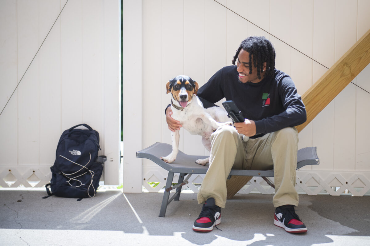 student sits on bench with beagle dog