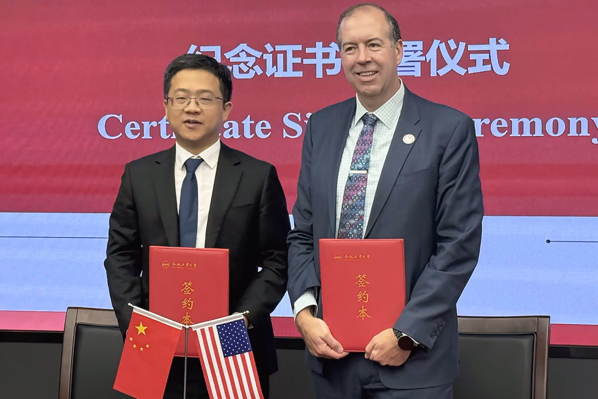 Hefei University of Technology President Wang Meng, left, and Clark University President John Magee hold red folders of newly signed document