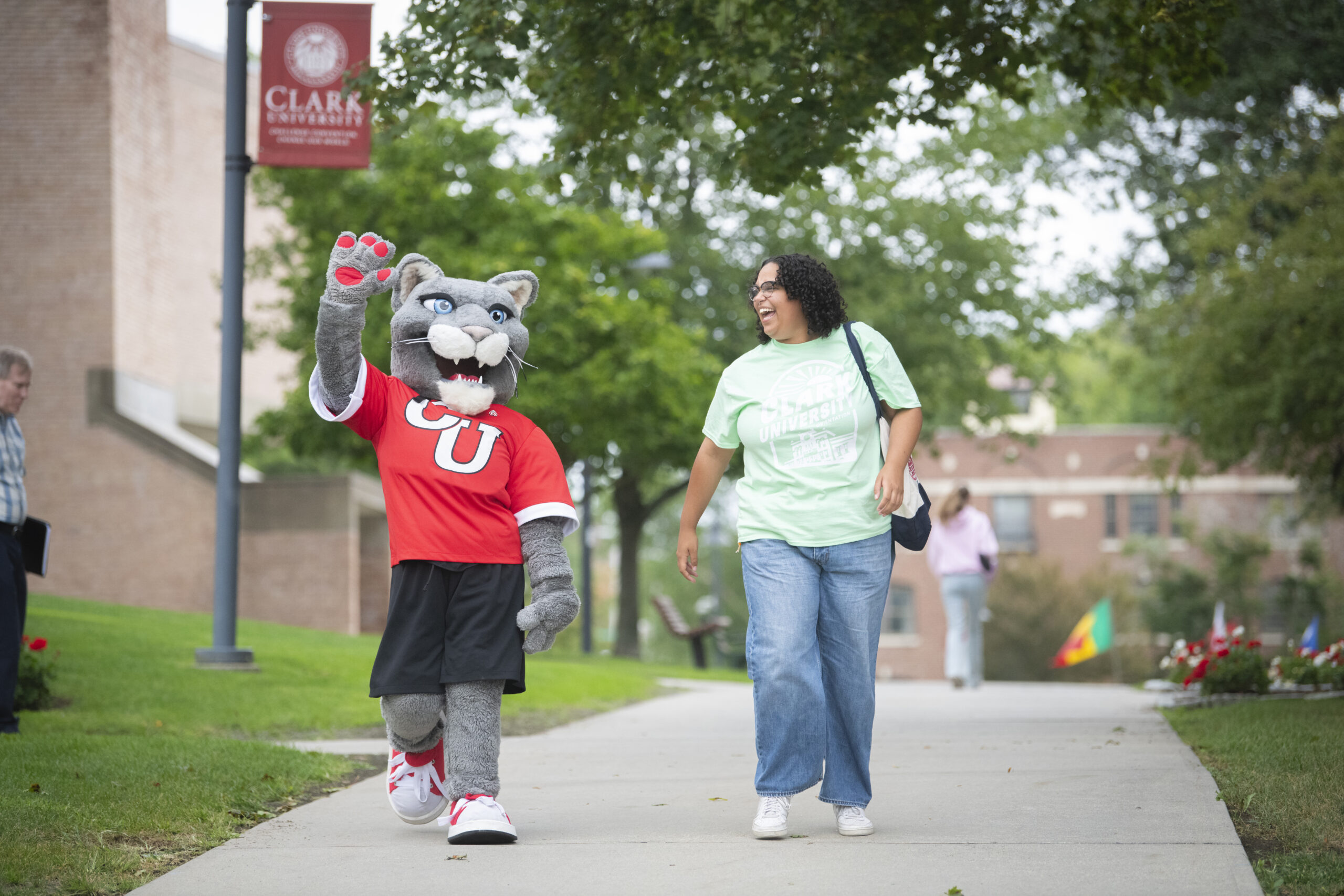 mascot and student walk on sidewalk
