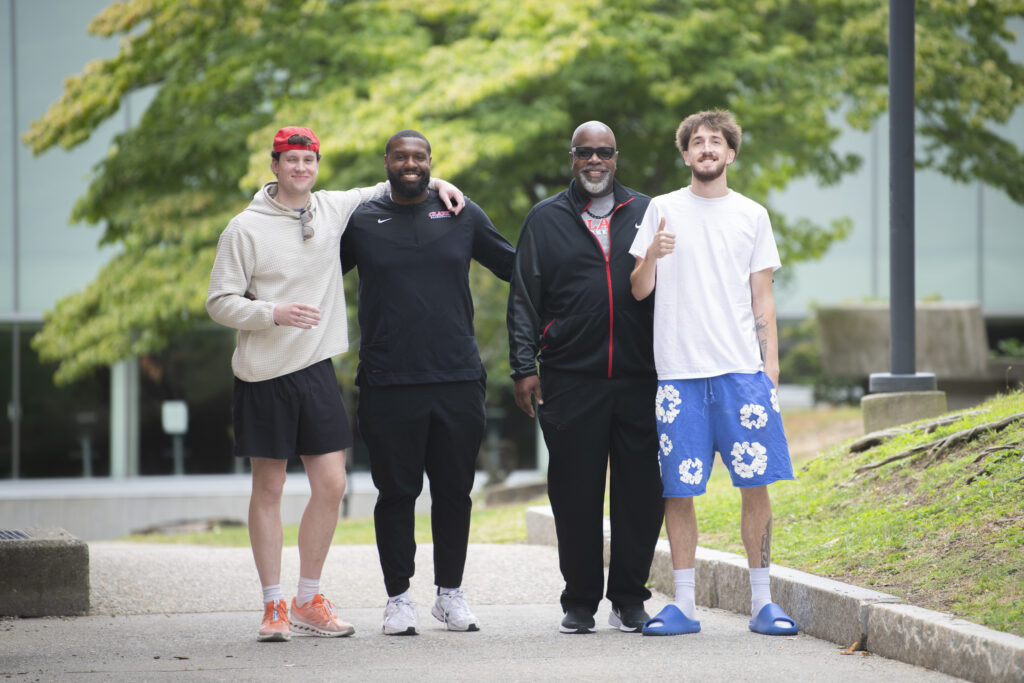 four people pose for photo on sidewalk