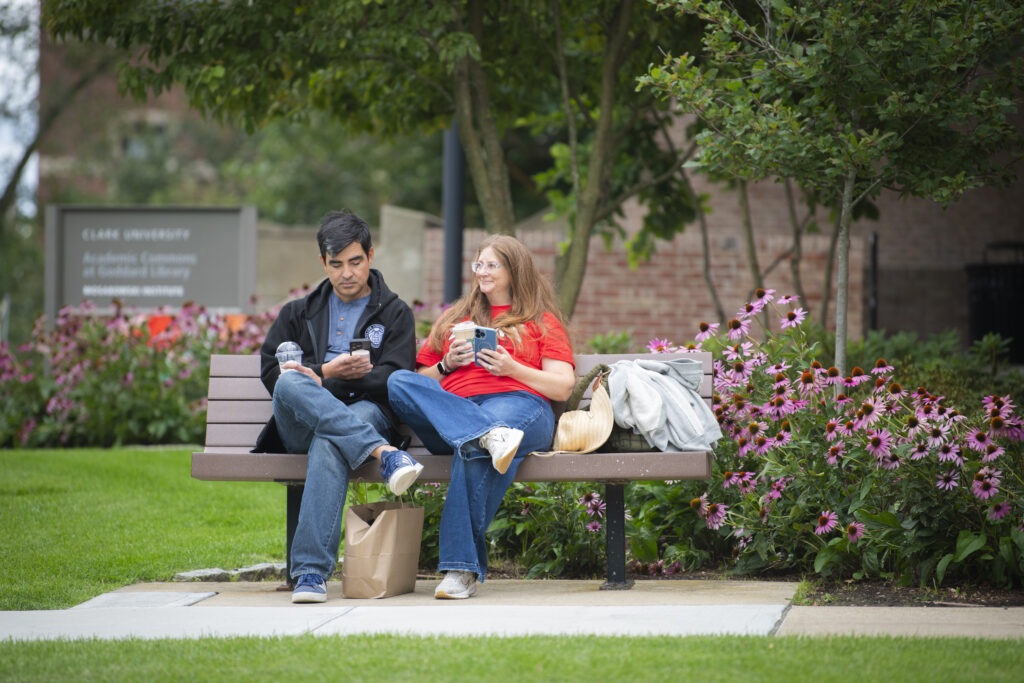 two people sitting on bench on college campus