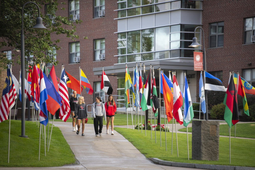 students walk on sidewalk near flags