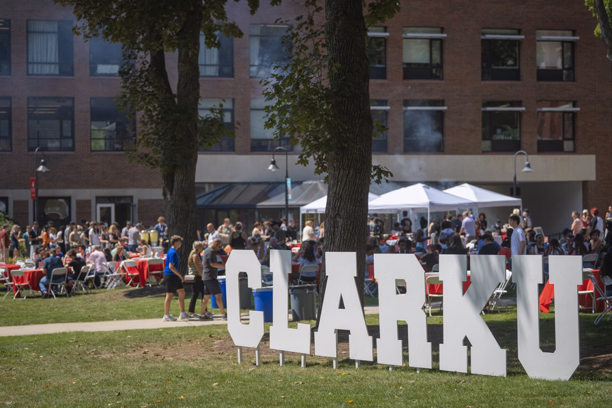 People gather for lunch on the campus green with large letters that say CLARK