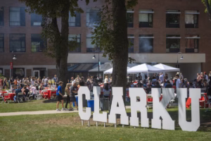 People gather for lunch on the campus green with large letters that say CLARK