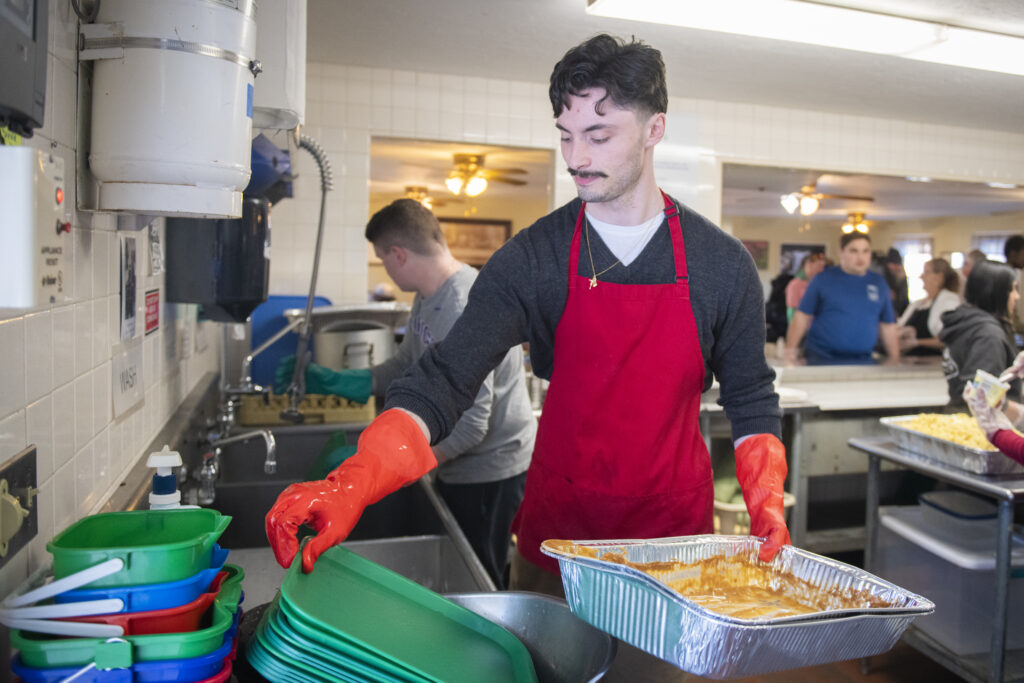 student cleans dishes at soup kitchen