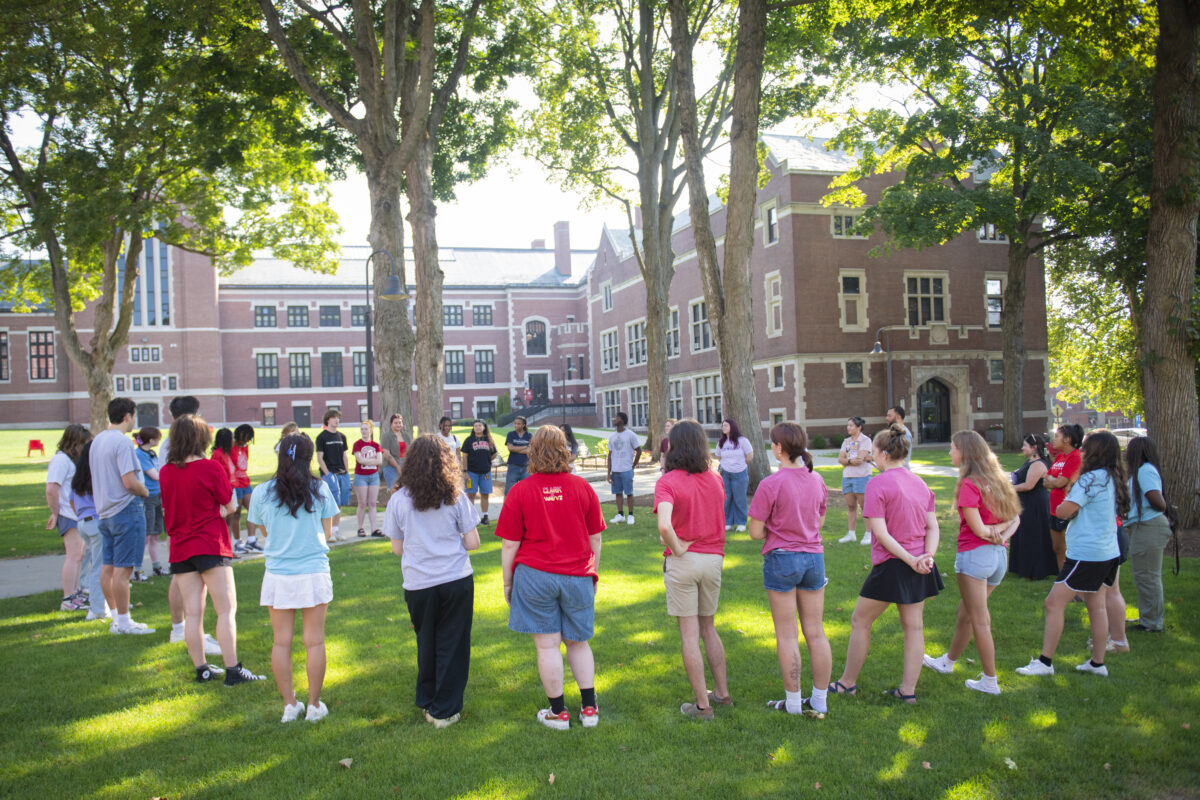 students stand in circle on campus green