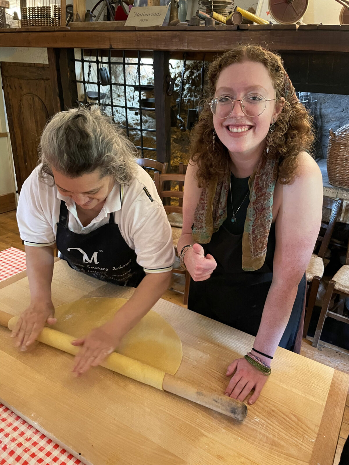 Clark student giving thumb's up in learning how to roll dough with chef