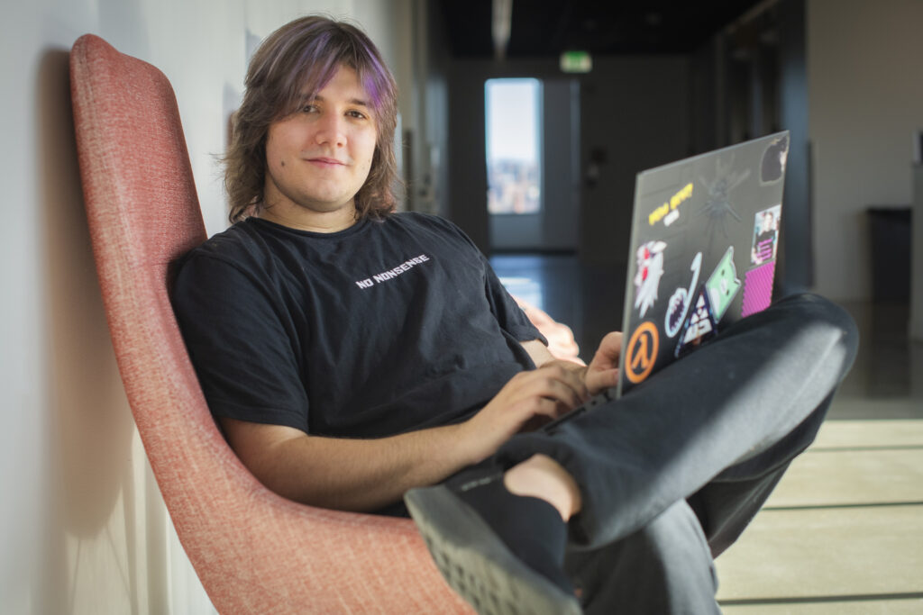 student sits in chair and types on laptop
