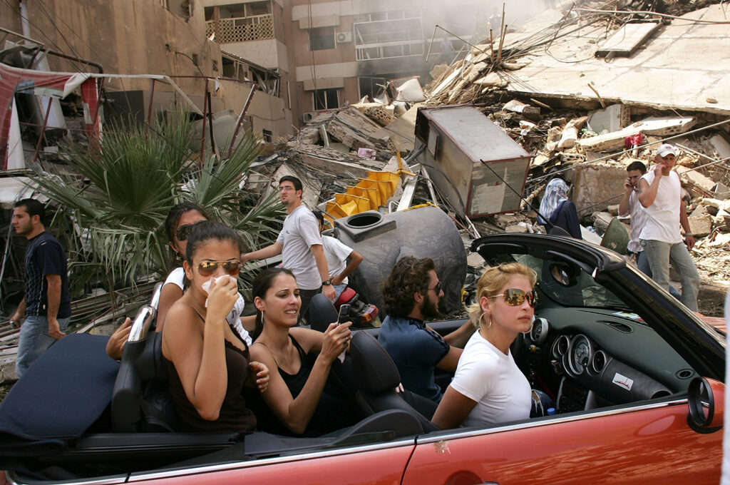 Affluent Lebanese drive down the street to look at a destroyed neighborhood August 15, 2006 in southern Beirut, Lebanon.  As the United Nations brokered cease fire between Israel and Hezbollah enters its first day, thousands of Lebanese returned to their homes and villages.
