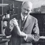 Robert Goddard in his Clark University lab with early steel combustion chamber and nozzle, circa 1920