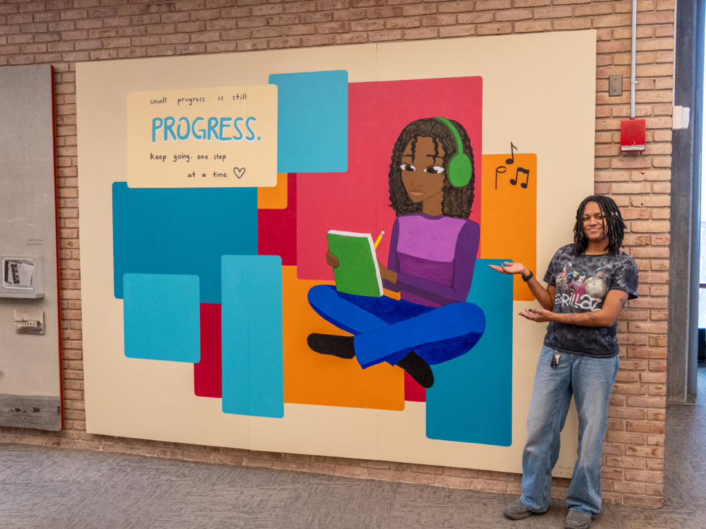 artist poses with mural