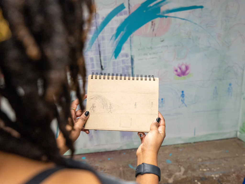 student holds sketchbook in studio