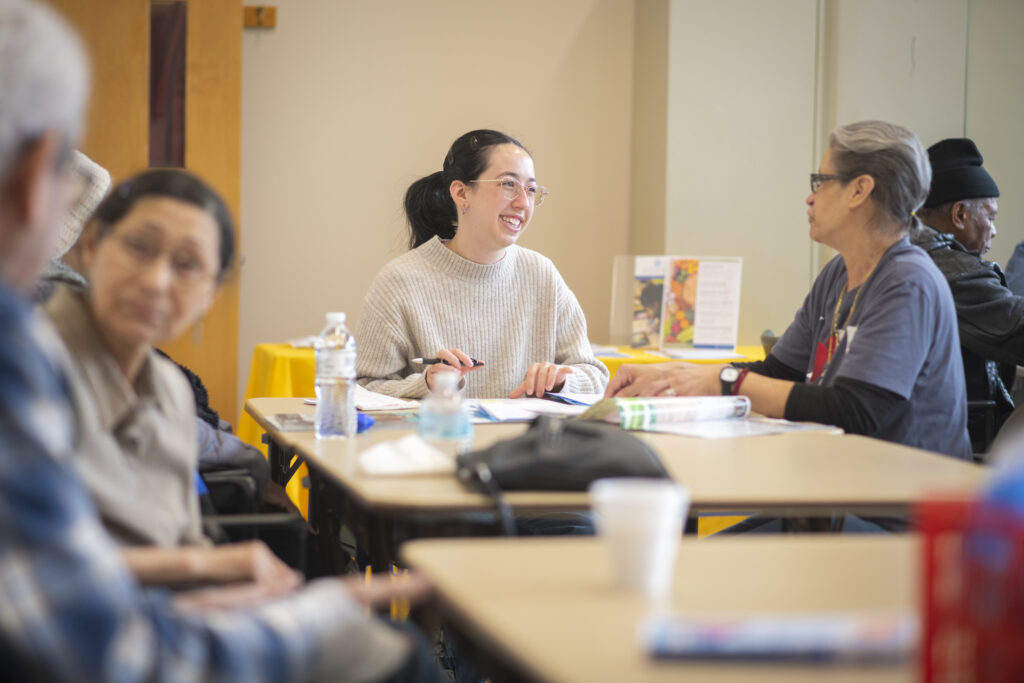 student sits at table with seniors