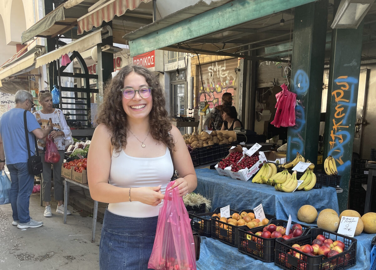 Student holding bag of cherries at a fruit stand
