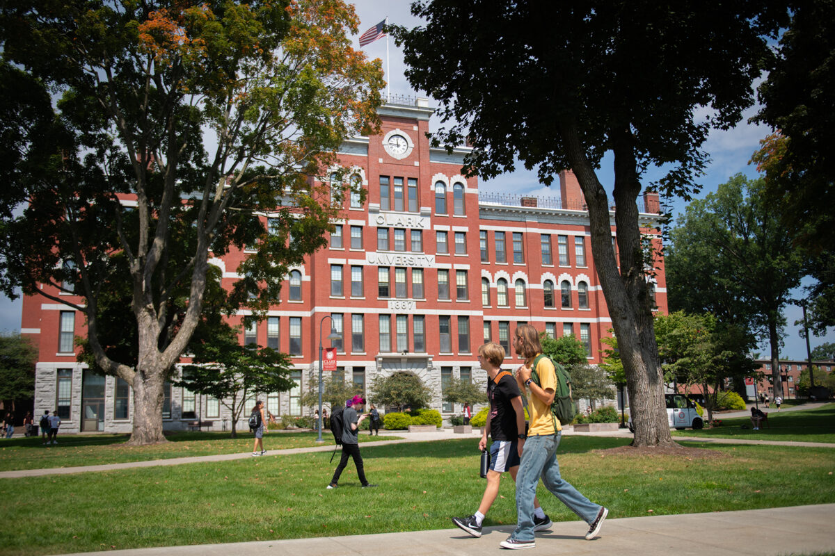 Student walking across Clark University campus in front of Jonas Clark Hall