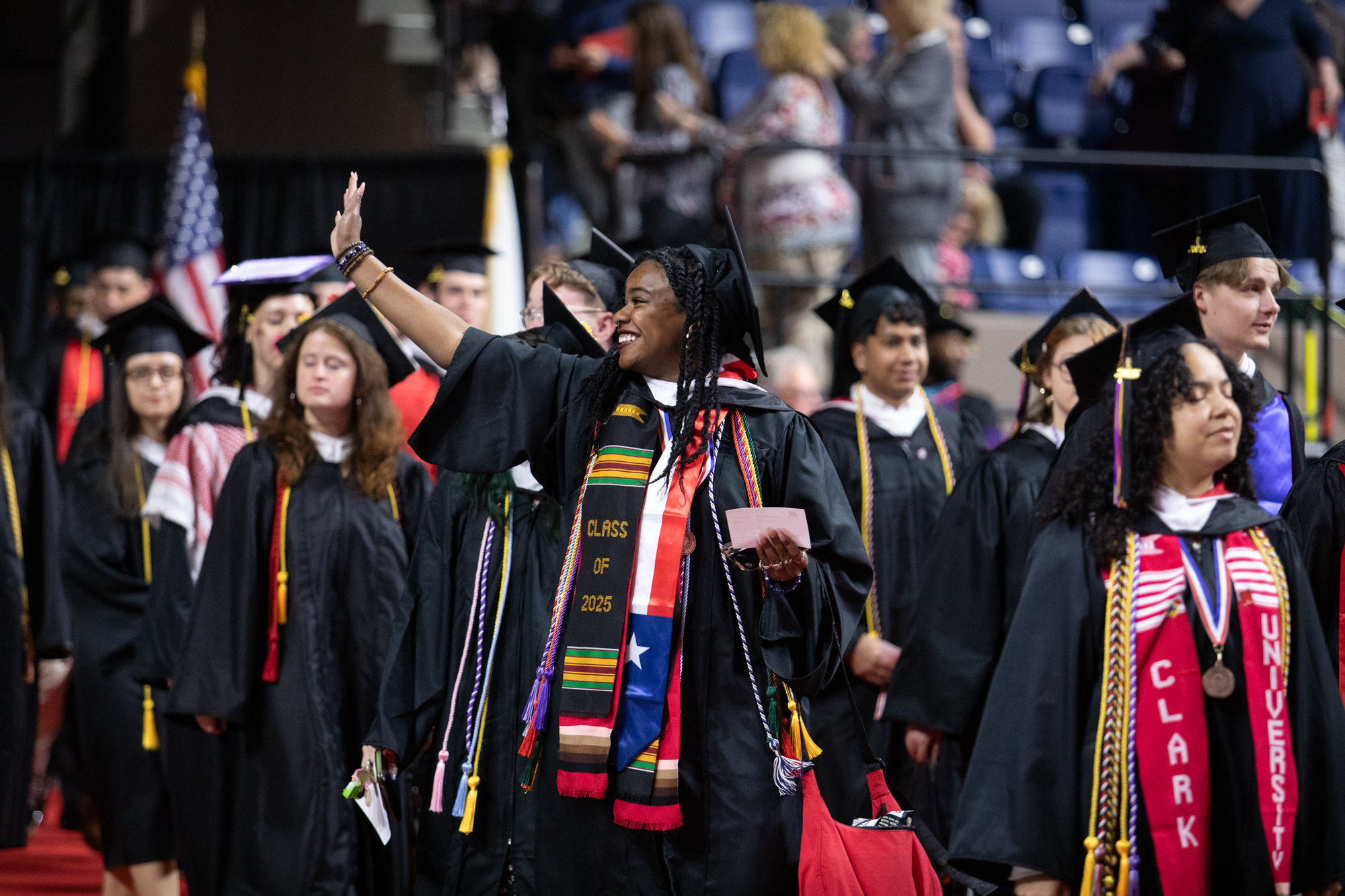 undergraduate students wave at graduation