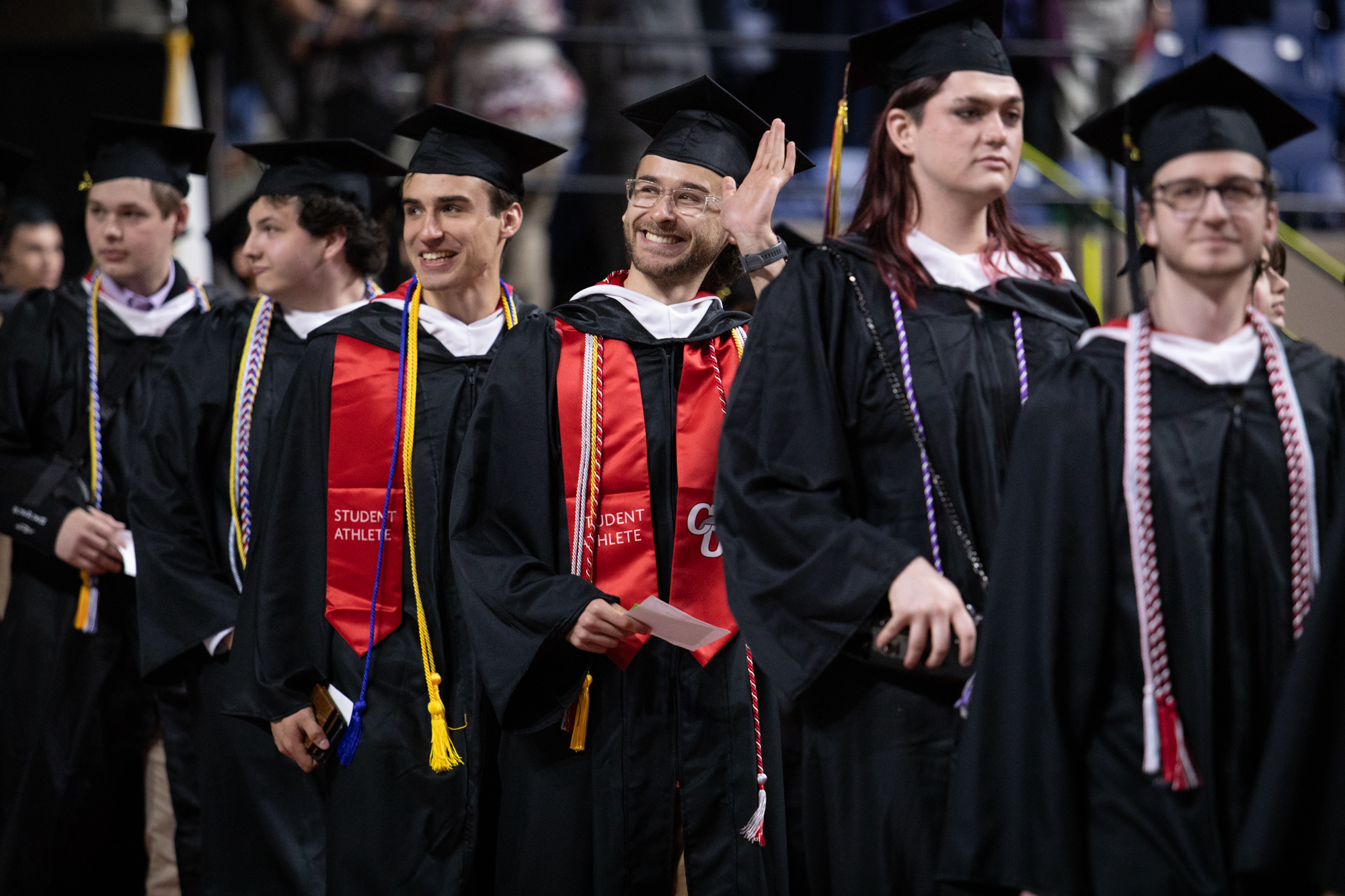 undergraduate students wave at graduation