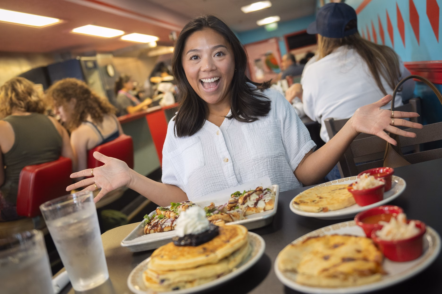 woman smiling at restaurant with pancakes and pupusas on table