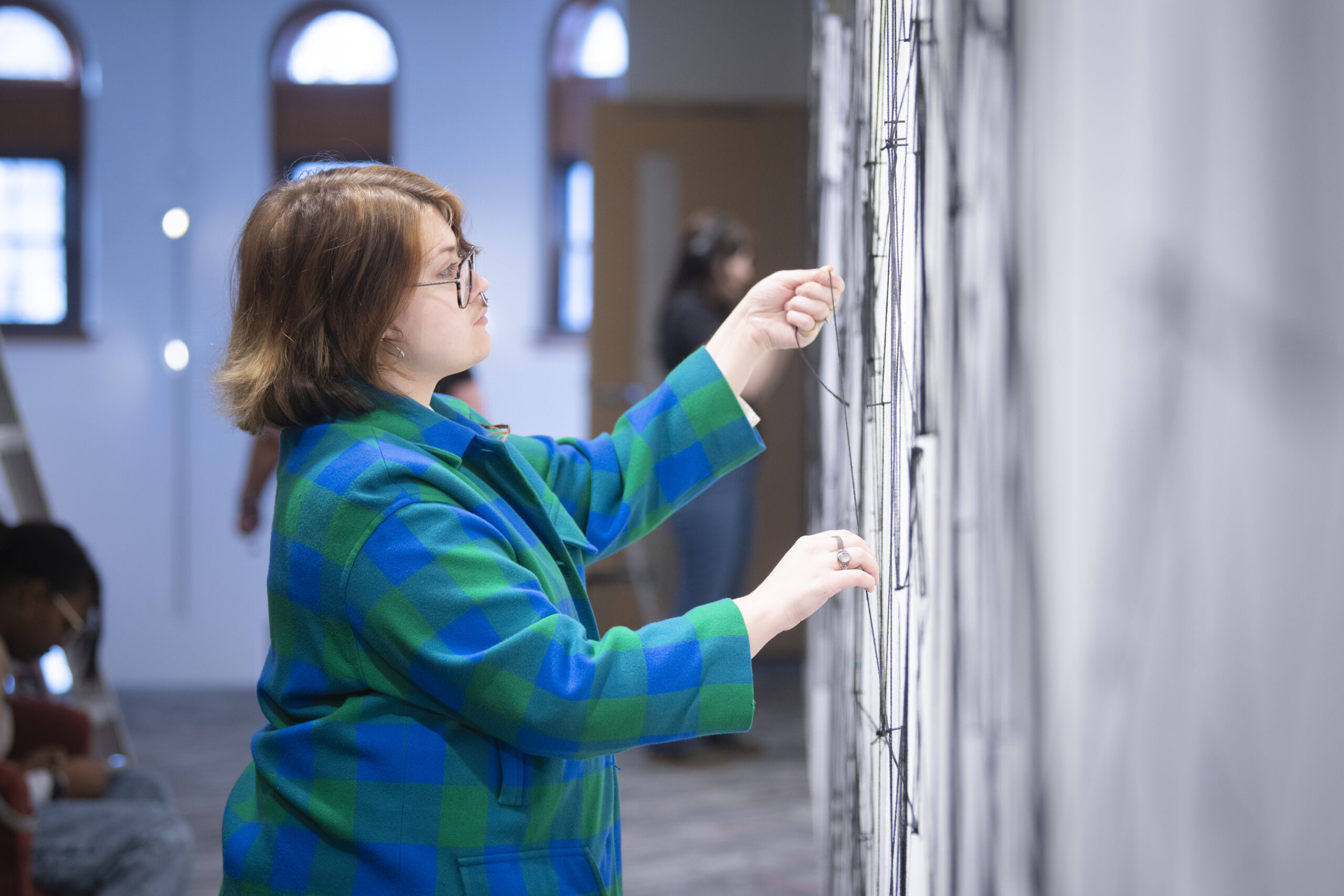 students assemble a mural of string and nail on wall