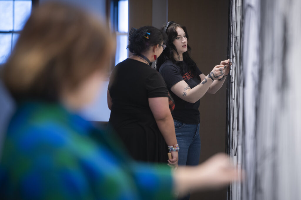 students assemble a mural of string and nail on wall