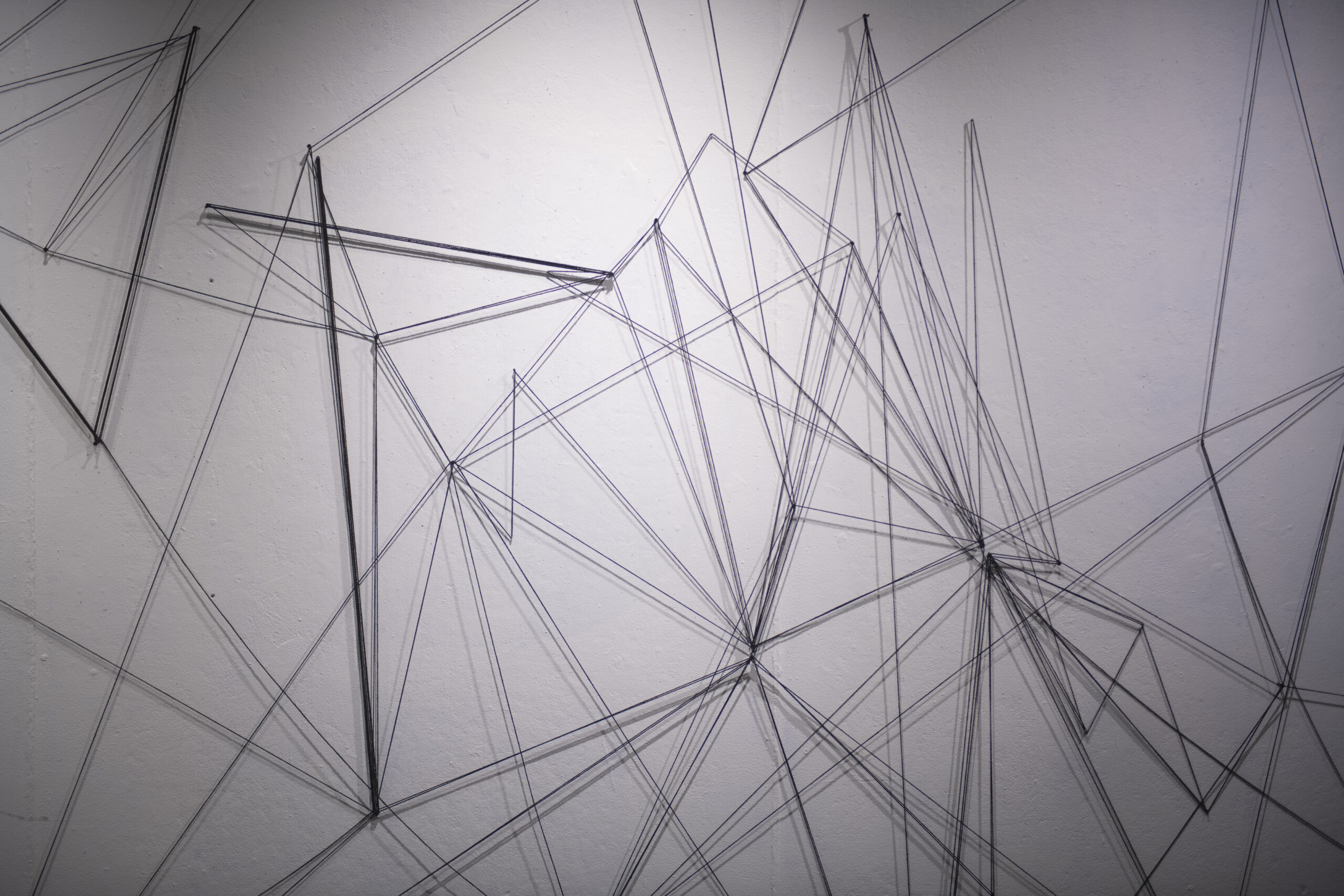 students assemble a mural of string and nail on wall