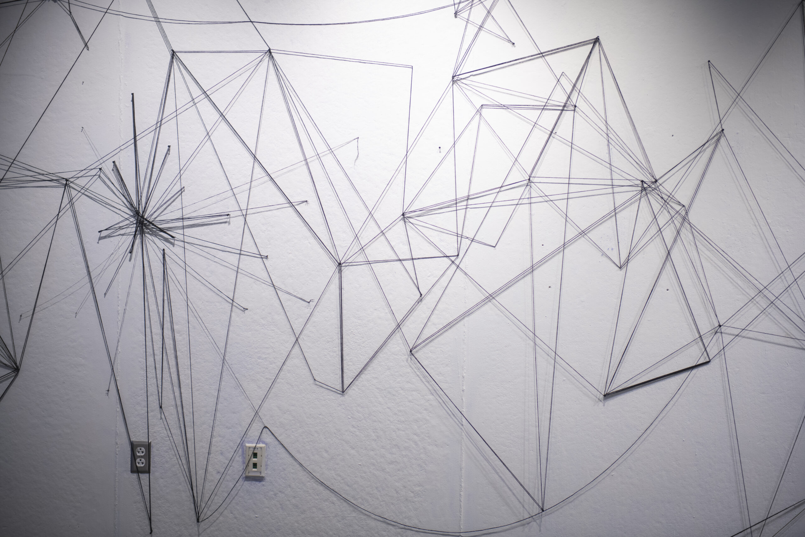 students assemble a mural of string and nail on wall