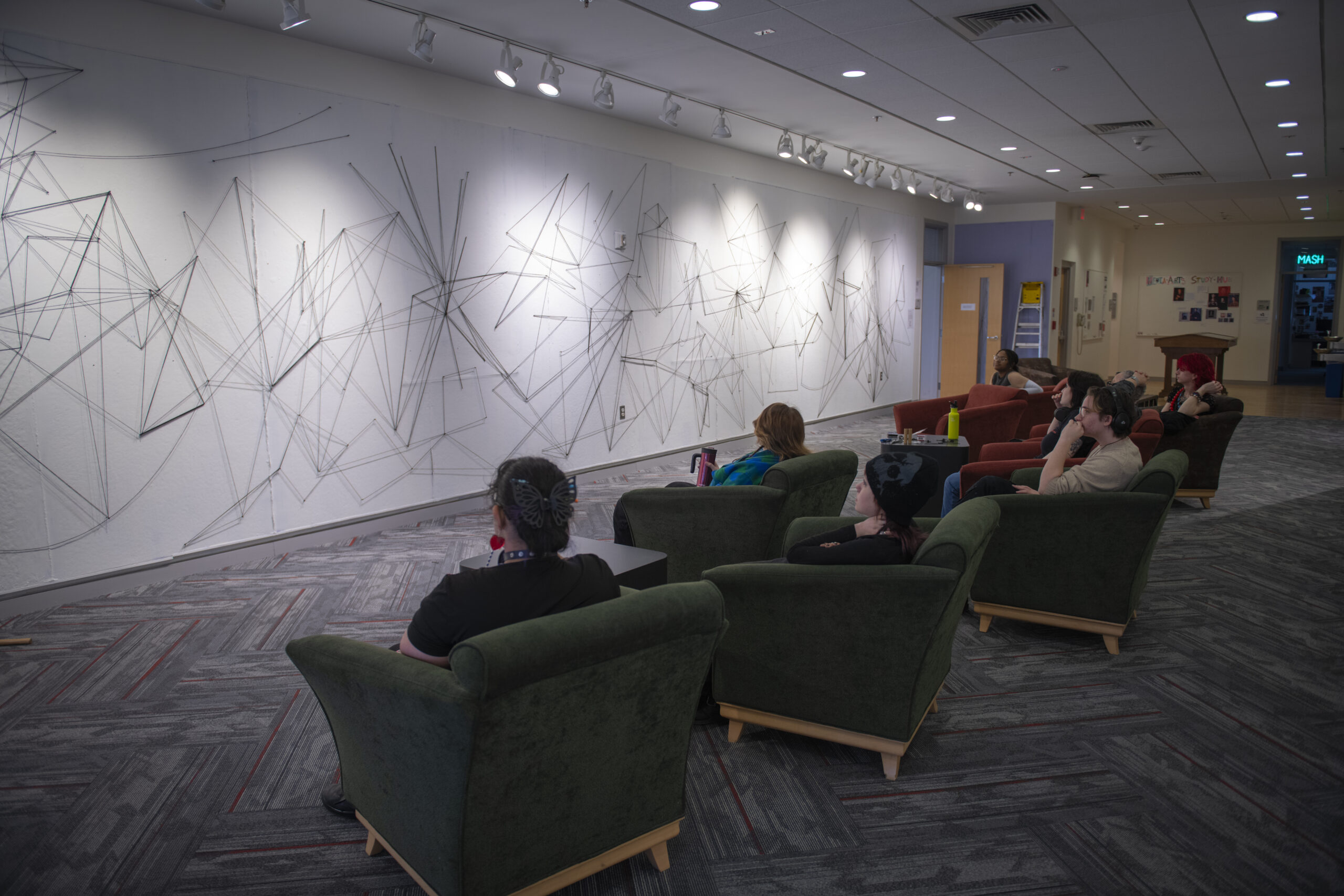 students assemble a mural of string and nail on wall