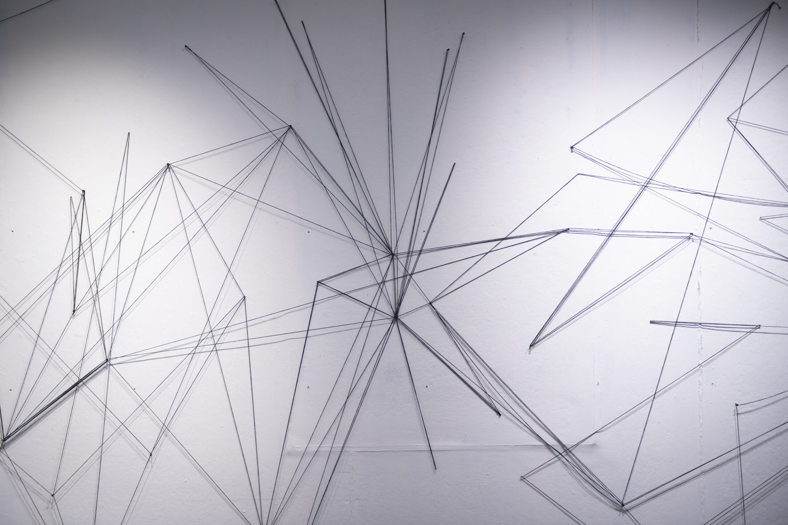 students assemble a mural of string and nail on wall