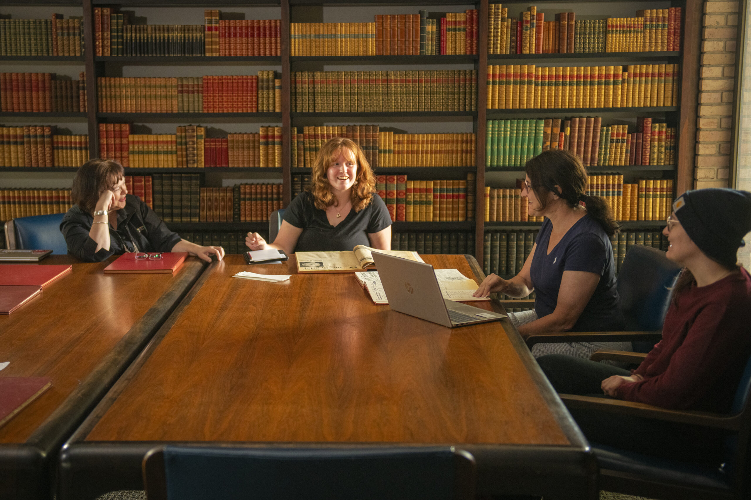 four people sit at table in library