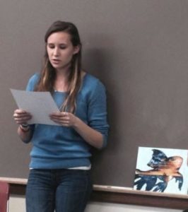 Hannah Corney, a Clark University first-year student, reads Norberto Stuart's poem "El pez muerto flota panza arriba" (The Dead Fish Floats Belly-Up), the inspiration for a painting that she presented to the poet. 