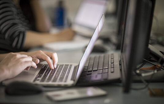 student typing in laptop