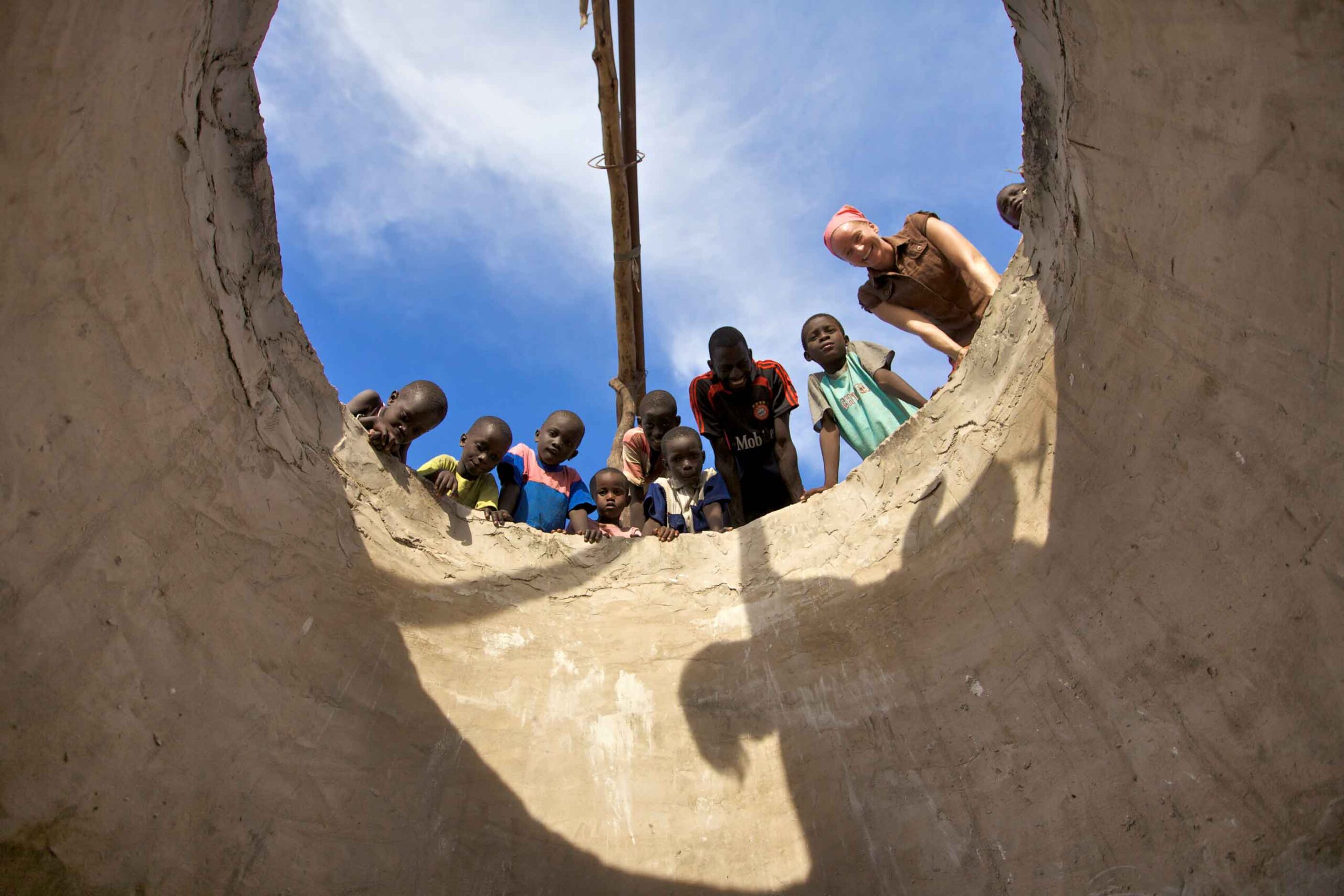 A Peace Corps Volunteer looking into a cistern with members of their host community