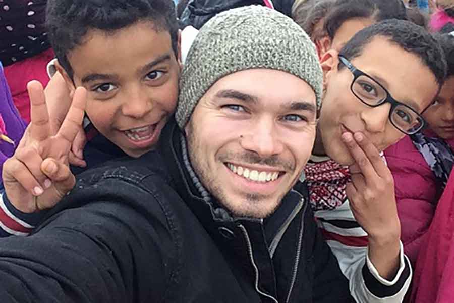 A Peace Corps volunteer posing for a selfie with two children