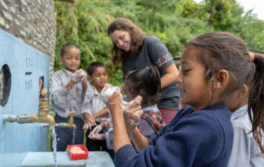 peace corps student working with children to wash their hands