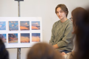 Student presenting several art peices on easel