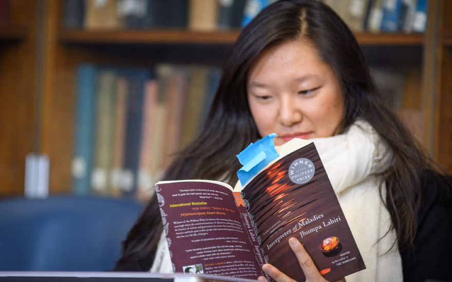 english student reading book in library