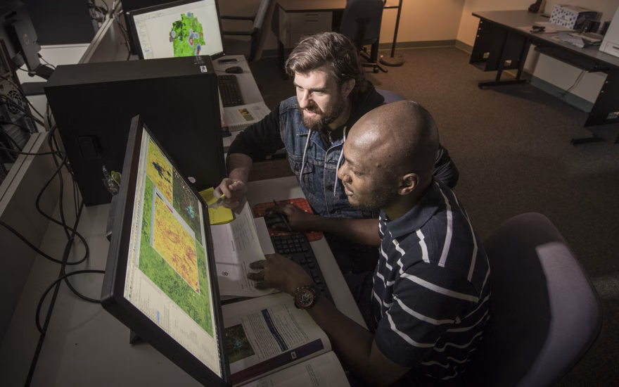 two students looking over geographic maps on computers