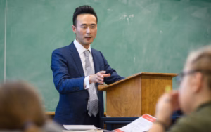 Professor Lex Lu in front of students at podium
