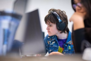 A student listens to audio during a game design fundamentals class