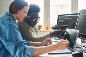 Two cybersecurity professionals conferring in front of their consoles