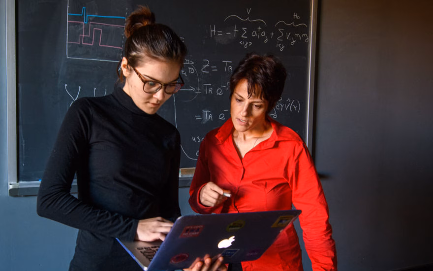 Physics professor with student looking over laptop