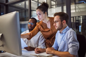 technology leadership - woman pointing to computer with two men next to her