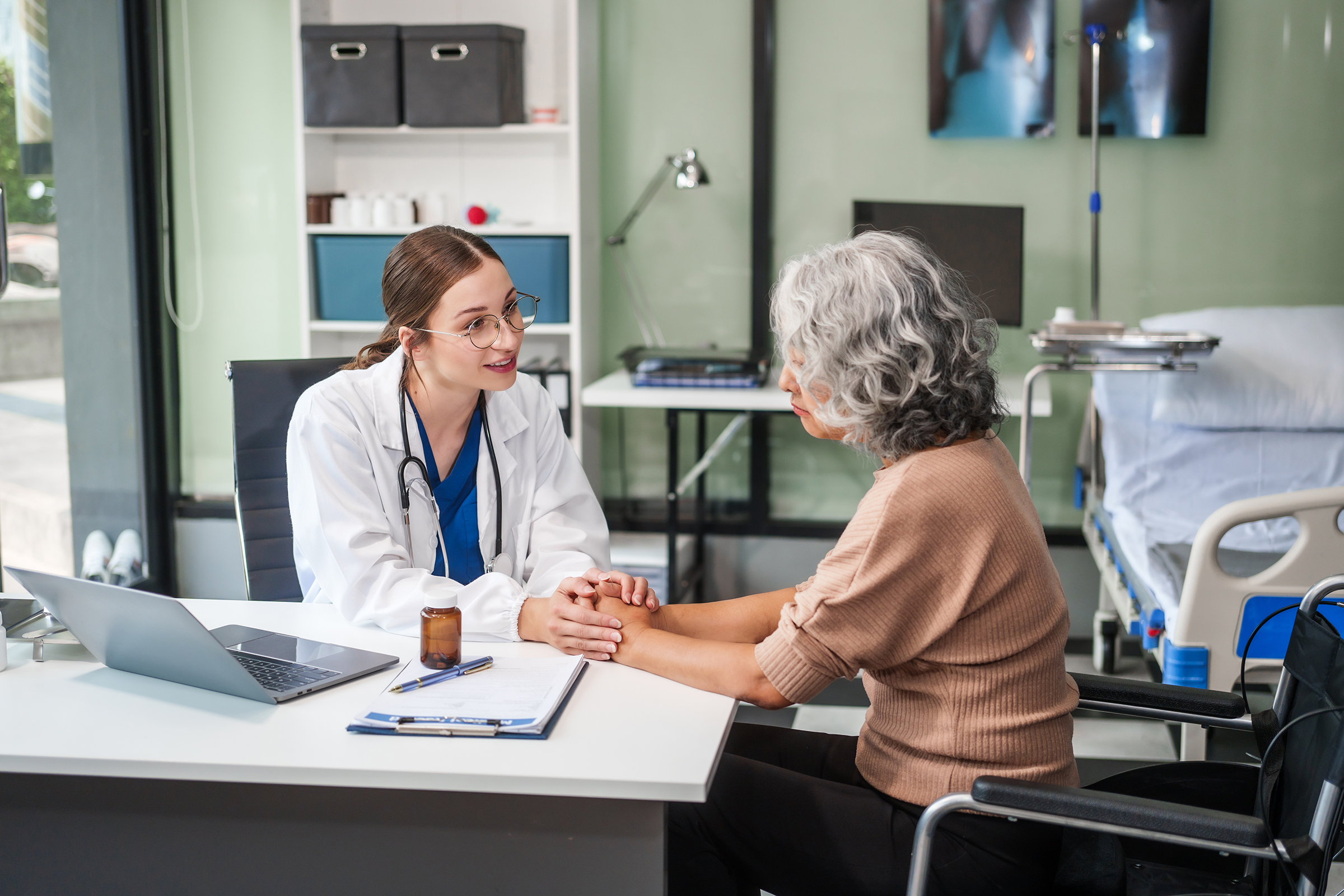 Caucasian female psychiatrist sits at her desk, providing mental health consultations and therapy sessions to her patients with empathy and expertise. elderly patient sit on wheelchair.