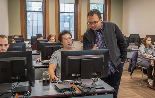 student with professor looking at computer screen