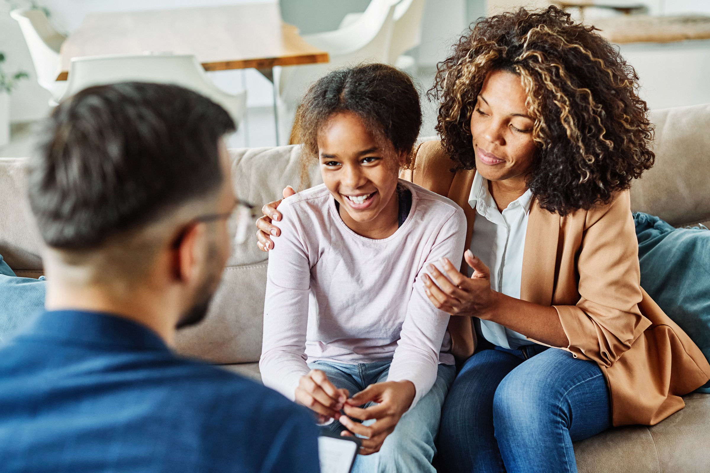 mother and child sitting on couch talking to psychologist